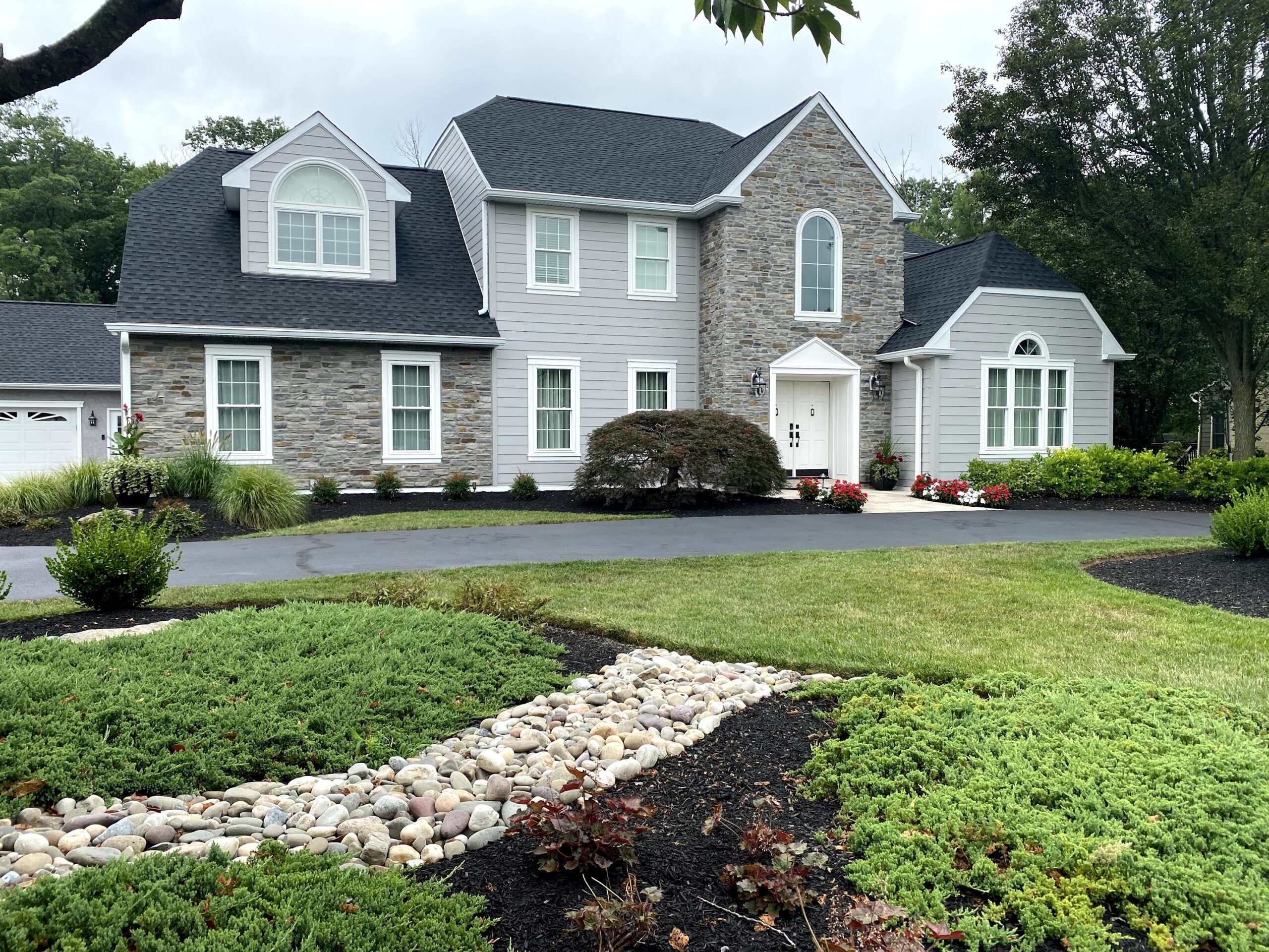 Large stone home with landscaping